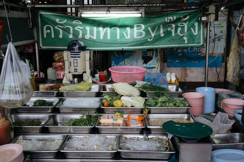 Street food stall in Bangkok with vegetables, noodles, and seafood