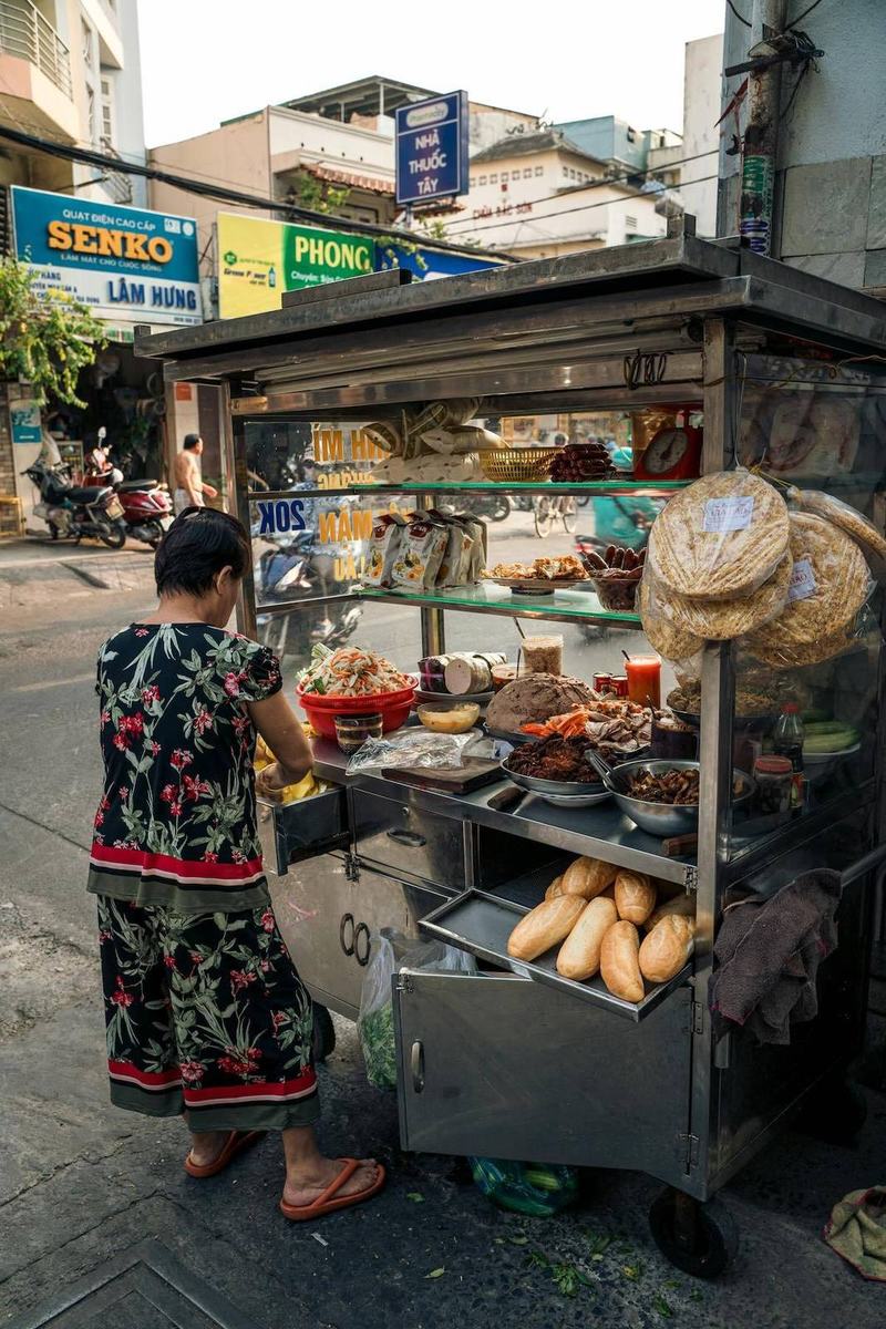 Street vendor preparing bánh mì in Hanoi with fresh ingredients and baguettes