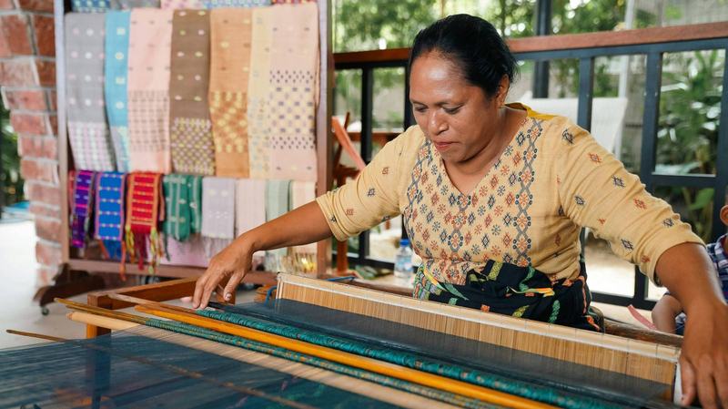 Lao woman weaving silk fabric on a traditional wooden loom