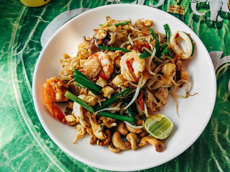 Plate of Pad Thai with shrimp, squid, lime, and cashew nuts